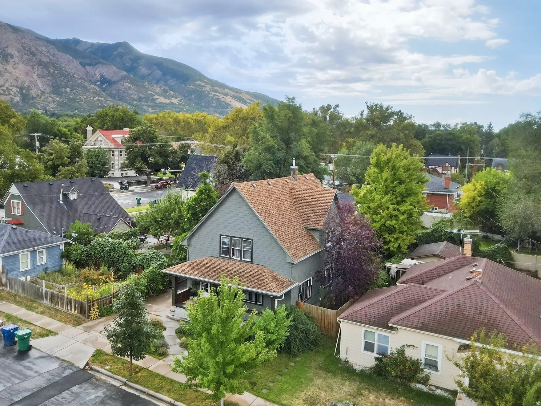 Mountain backdrop, residential street, mature trees, single-family home with established landscaping.