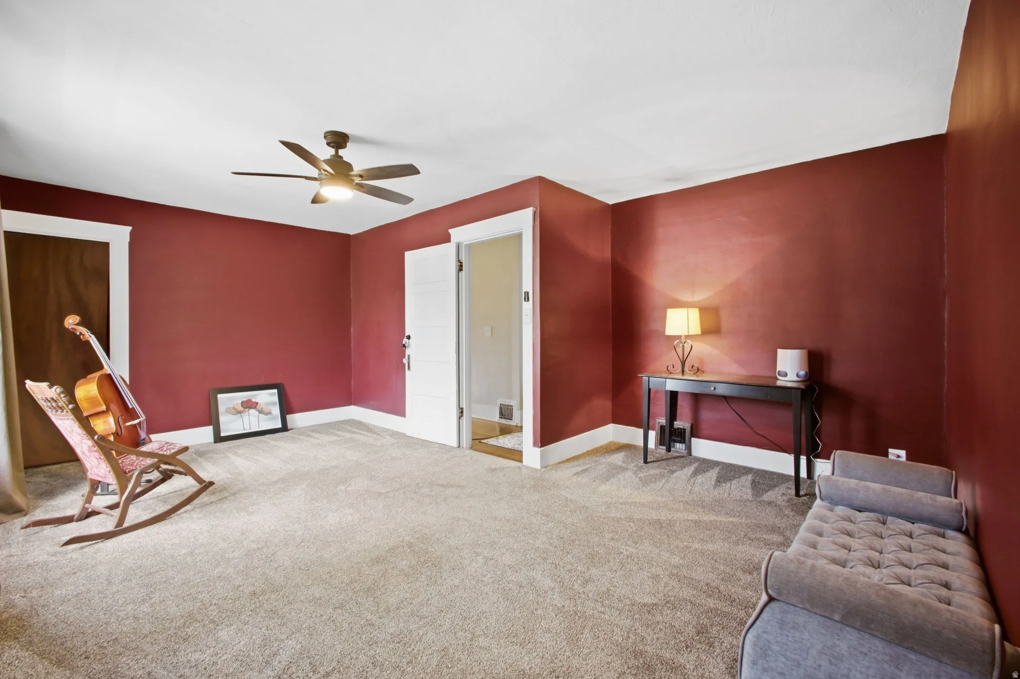 Spacious master bedroom with two closets, lush carpeting, ceiling fan with integrated lighting, and warm painted walls.