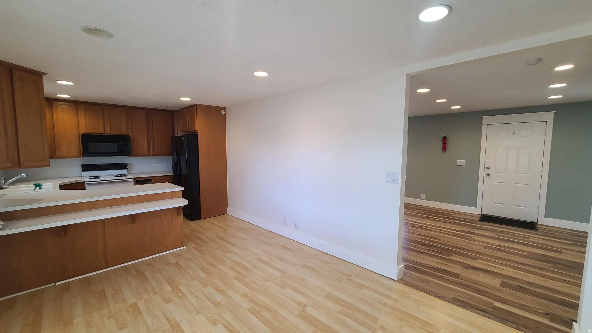 Kitchen featuring wood cabinetry, white countertops, built-in microwave, and wood-finish flooring