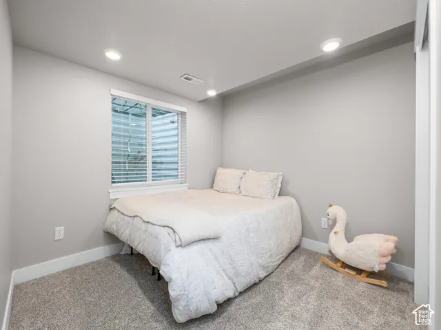 Bedroom featuring neutral wall paint, recessed lighting, a single window with blinds, and gray carpet flooring