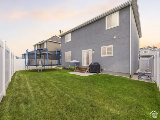 Spacious backyard featuring a manicured lawn, full vinyl privacy fencing, and concrete patio with wood steps