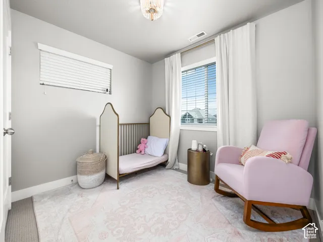 Room featuring a large window with white blinds and drapes, light gray painted walls, and a contemporary ceiling light fixture