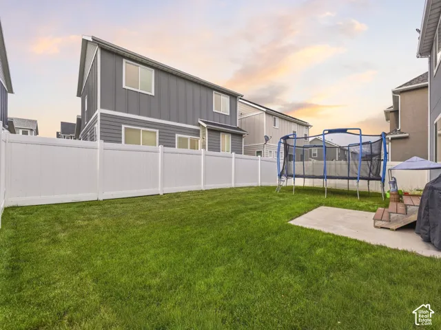 Expansive backyard featuring a manicured lawn, full privacy fencing, and a concrete patio pad
