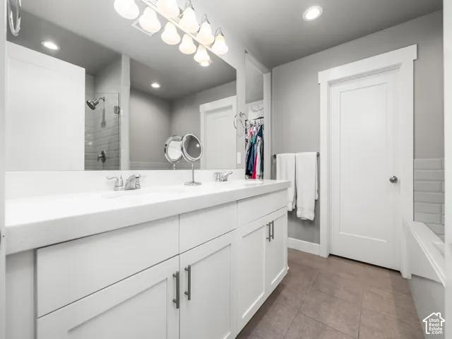 Double vanity with white cabinetry, integrated sinks, chrome fixtures, and a large mirror