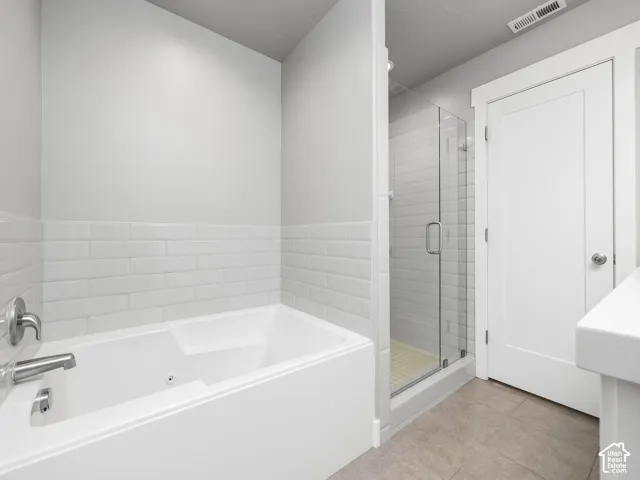 Bathroom featuring a white subway tile surround, a built-in bathtub with polished chrome fixtures, and a glass-enclosed shower with a tiled base