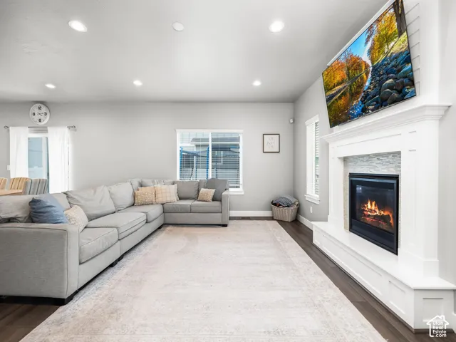 Living area featuring wood-finish flooring, recessed lighting, and a prominent fireplace with a white mantel and stone tile surround