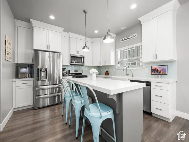 Modern kitchen featuring white shaker-style cabinetry with crown molding, stainless steel appliances, and a light blue tile backsplash
