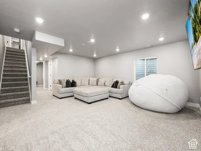 Spacious recreational room with light gray carpeting and recessed lighting