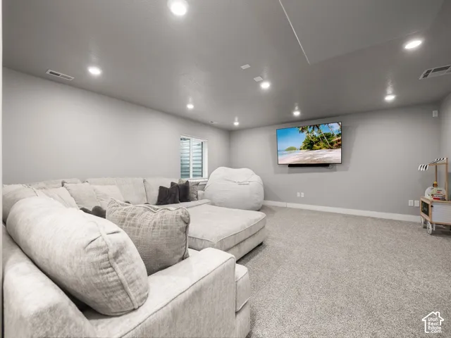 Spacious room featuring light gray walls, recessed lighting, and a wall-mounted display