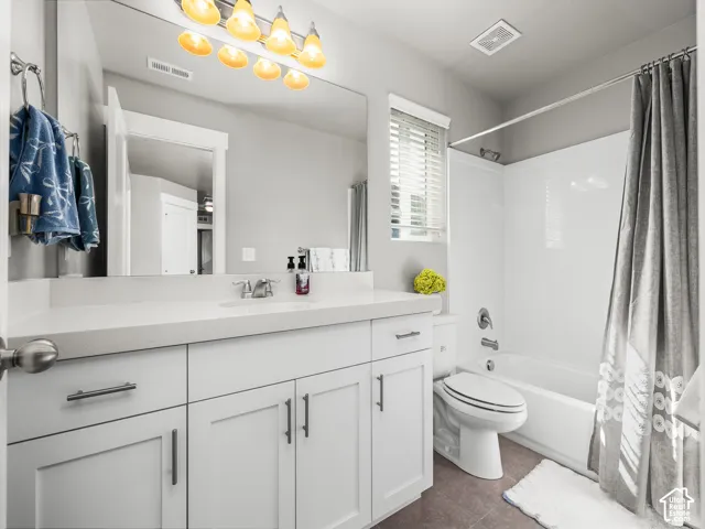 Bathroom featuring a white vanity with a light-toned countertop, a large wall mirror, and modern overhead lighting