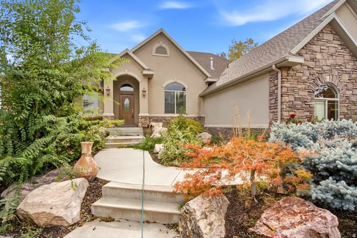 Stucco and stone exterior with arched windows, a wooden entry door, and a concrete pathway with steps