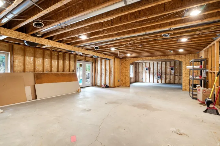 Unfinished basement with exposed wood joists and concrete flooring