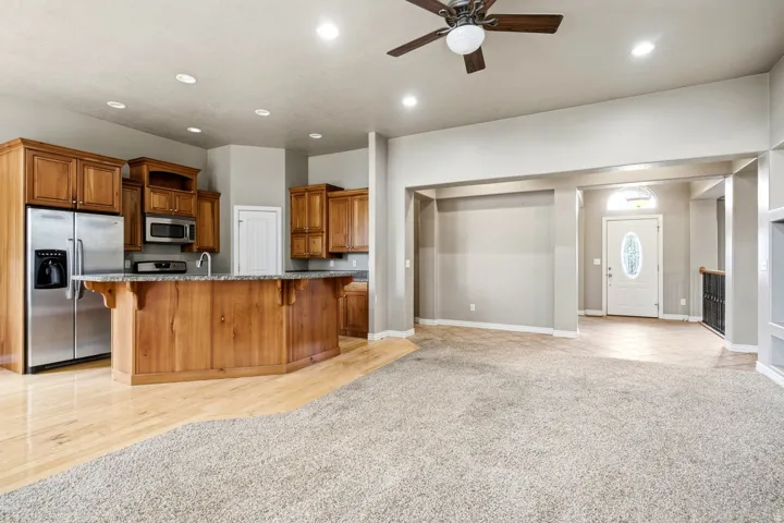Kitchen island with wood cabinetry, stainless steel appliances, and recessed lighting