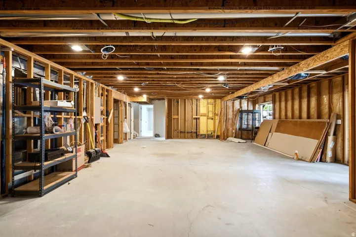 Unfinished basement featuring exposed wood framing, concrete flooring, and recessed lighting