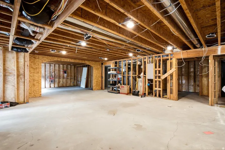 Unfinished basement featuring exposed wood joists, concrete flooring, recessed lighting, and framed interior walls