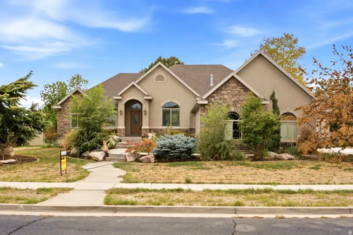 Stucco and stone exterior with arched windows, a covered entry, and a gabled roofline