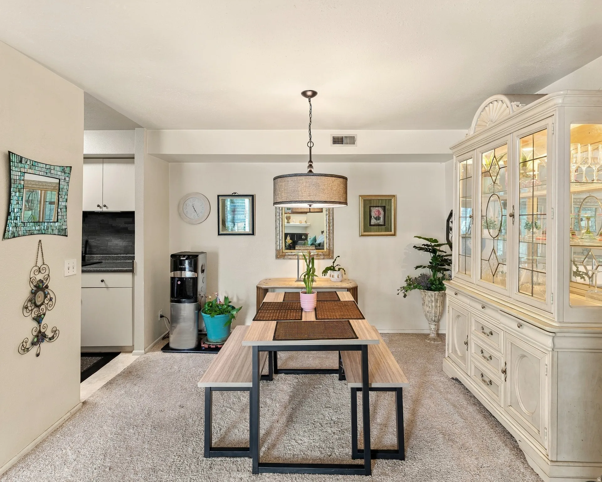 Recessed lighting, neutral wall tones, a built-in display cabinet with glass-paneled doors, and a decorative pendant light with a drum shade