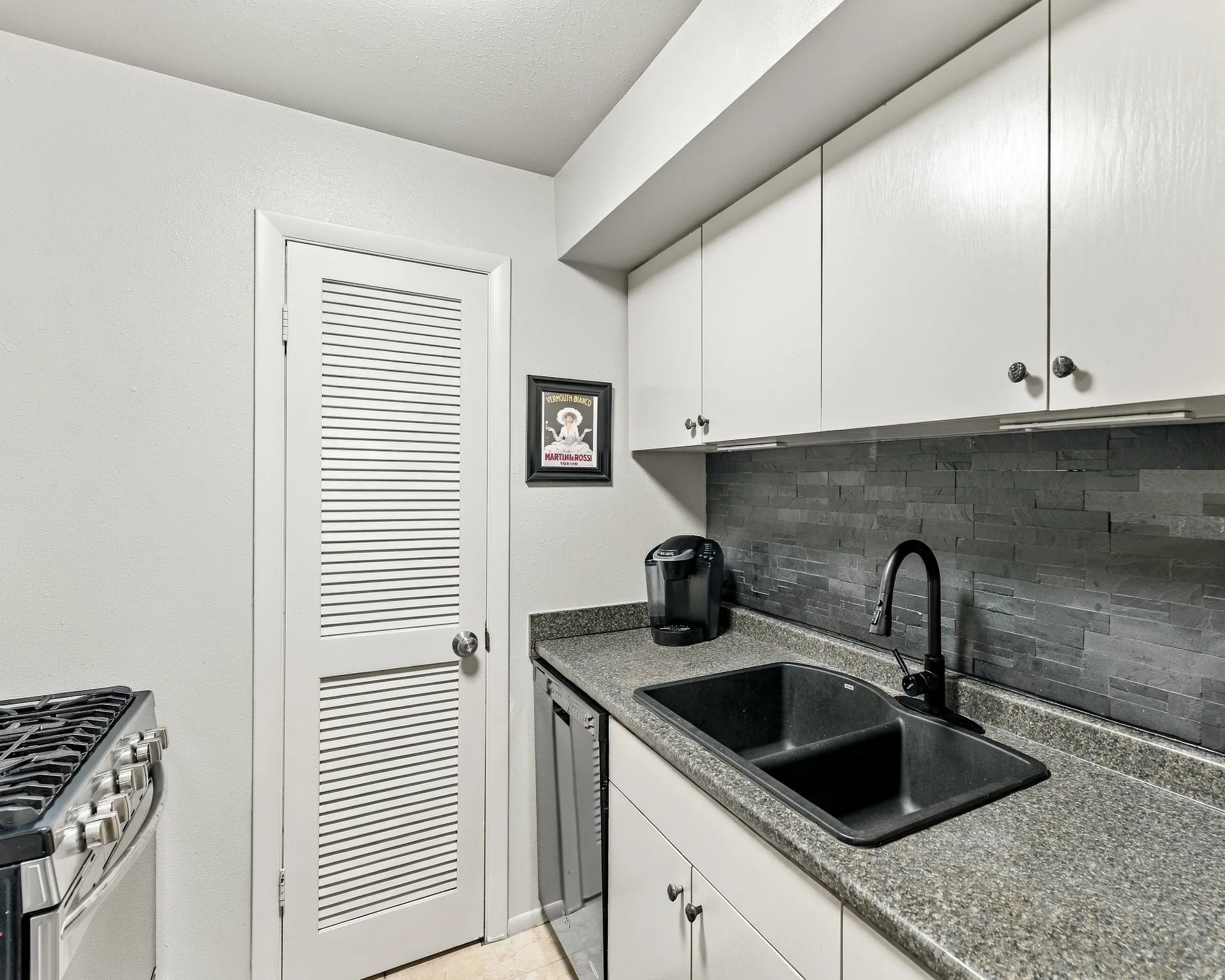 Kitchen featuring white cabinetry, a black dual-basin sink, and a black faucet
