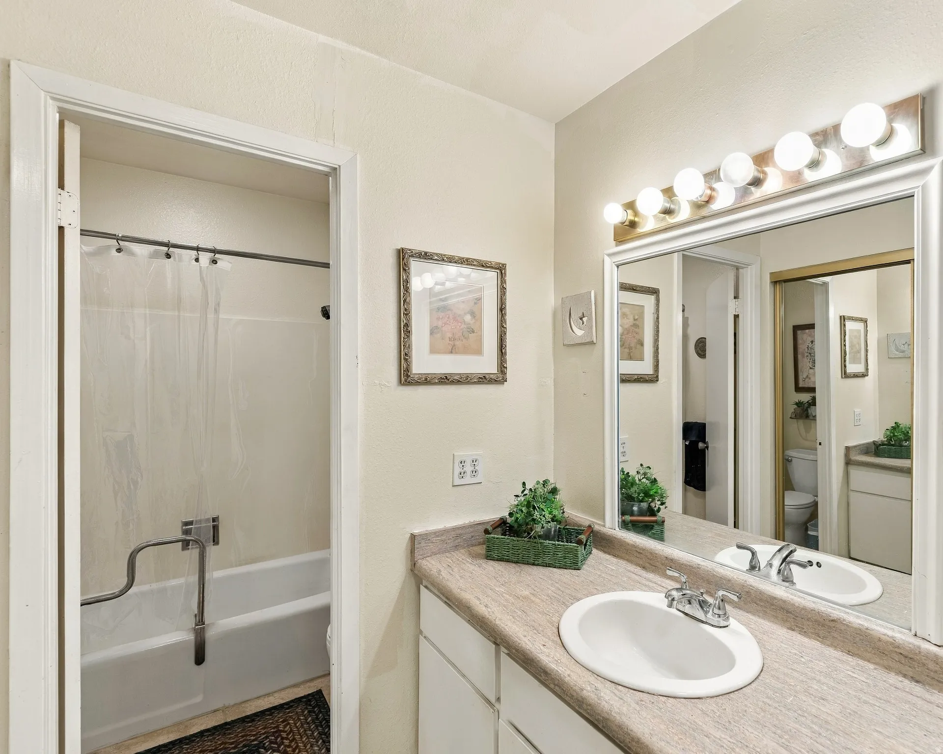 Bathroom featuring a vanity with a white oval sink, chrome faucet, and a large wall-mounted mirror
