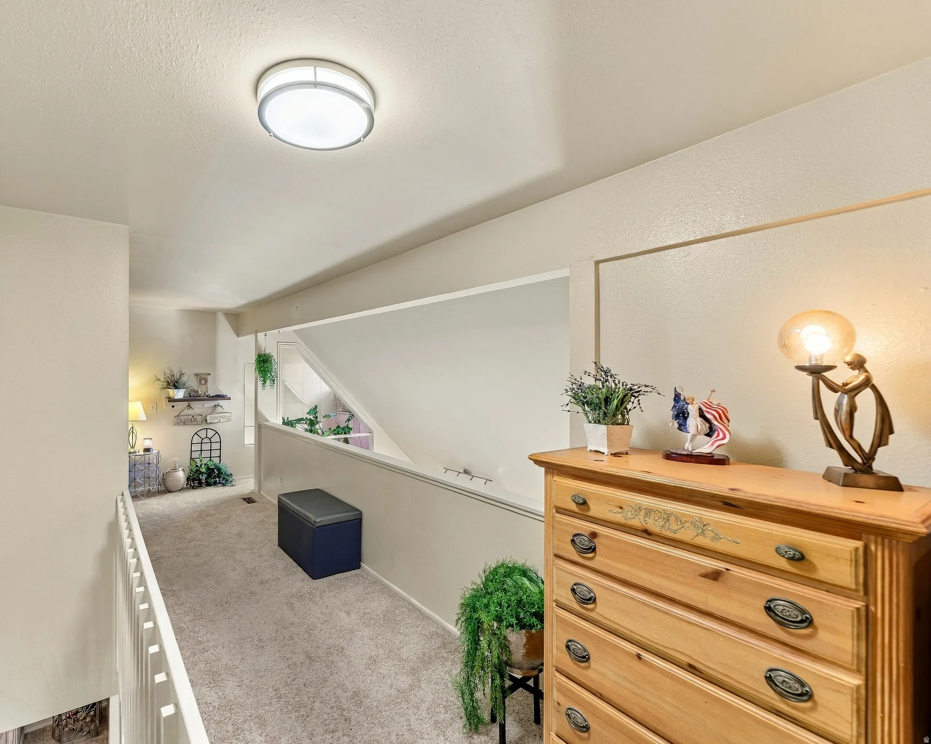Carpeted hallway featuring a flush-mount ceiling light and white railing