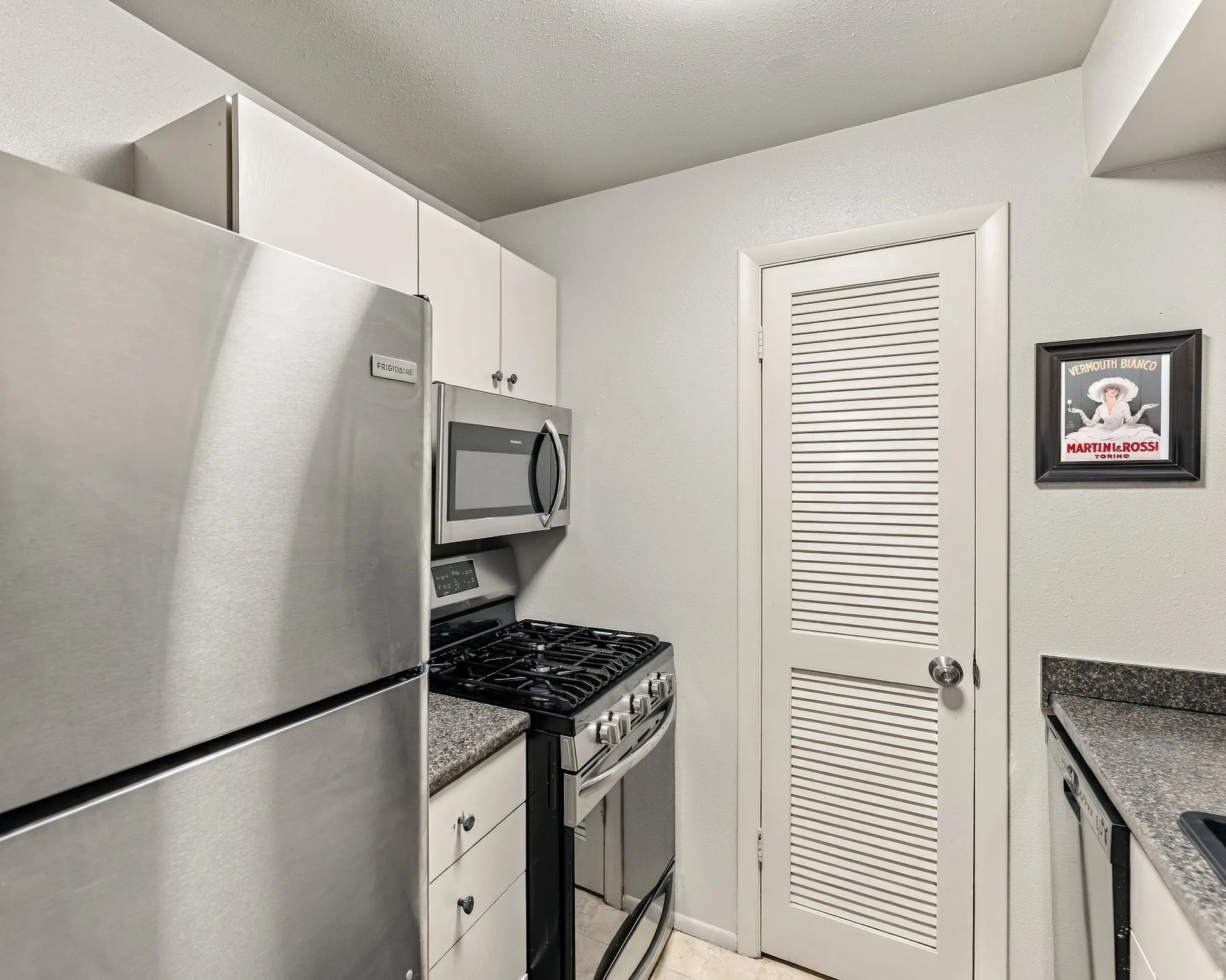 Stainless steel refrigerator, built-in microwave, gas range, wood-finish cabinetry, and solid surface countertops