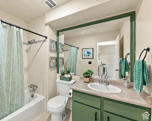 Bathroom featuring a bathtub with shower, vanity with an integrated sink, green-painted cabinetry, and a framed mirror