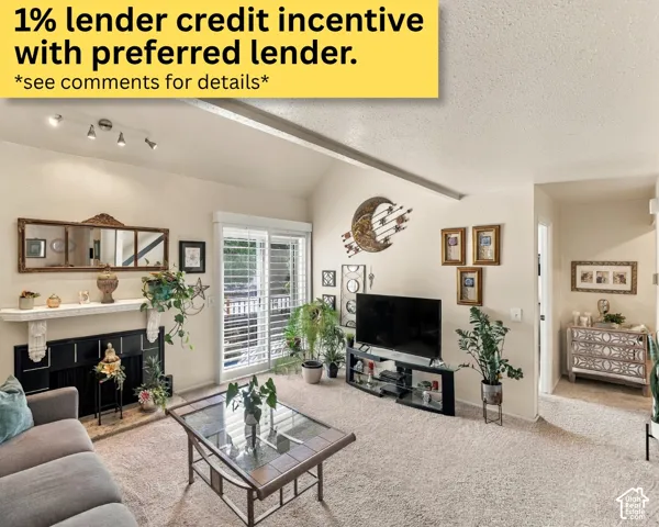 Vaulted ceiling with exposed beam, fireplace with decorative mantel, glass sliding doors, track lighting, and carpeted flooring