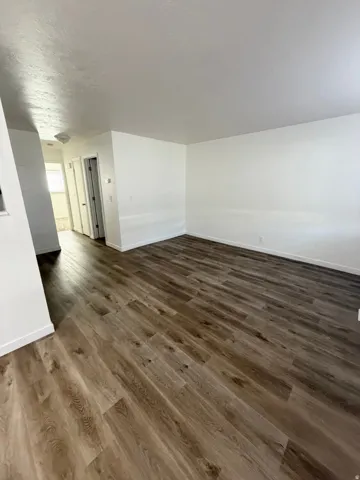 Wood-finish flooring throughout, bright white walls, and a recessed overhead light fixture