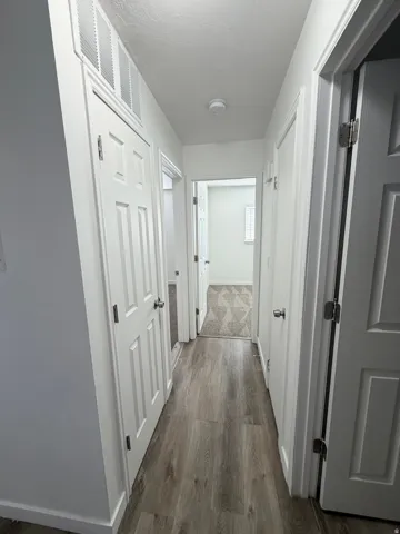 Hallway featuring wood-finish flooring, white panel doors, and neutral wall tones