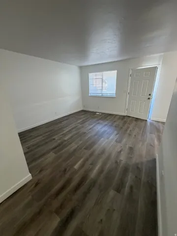 Wood-finish flooring, white walls, and a single window with blinds