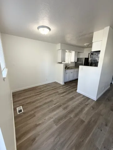 Kitchenette featuring white cabinetry, stainless steel appliances, and wood-finish flooring