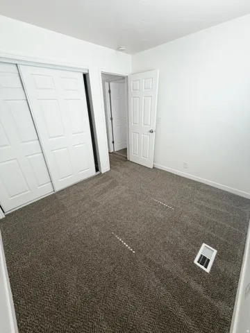 Carpeted room featuring a white paneled door, sliding closet doors, and white walls