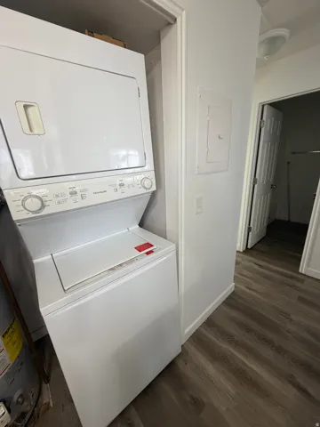 Stackable washer and dryer unit, wood-finish flooring, and white interior doors