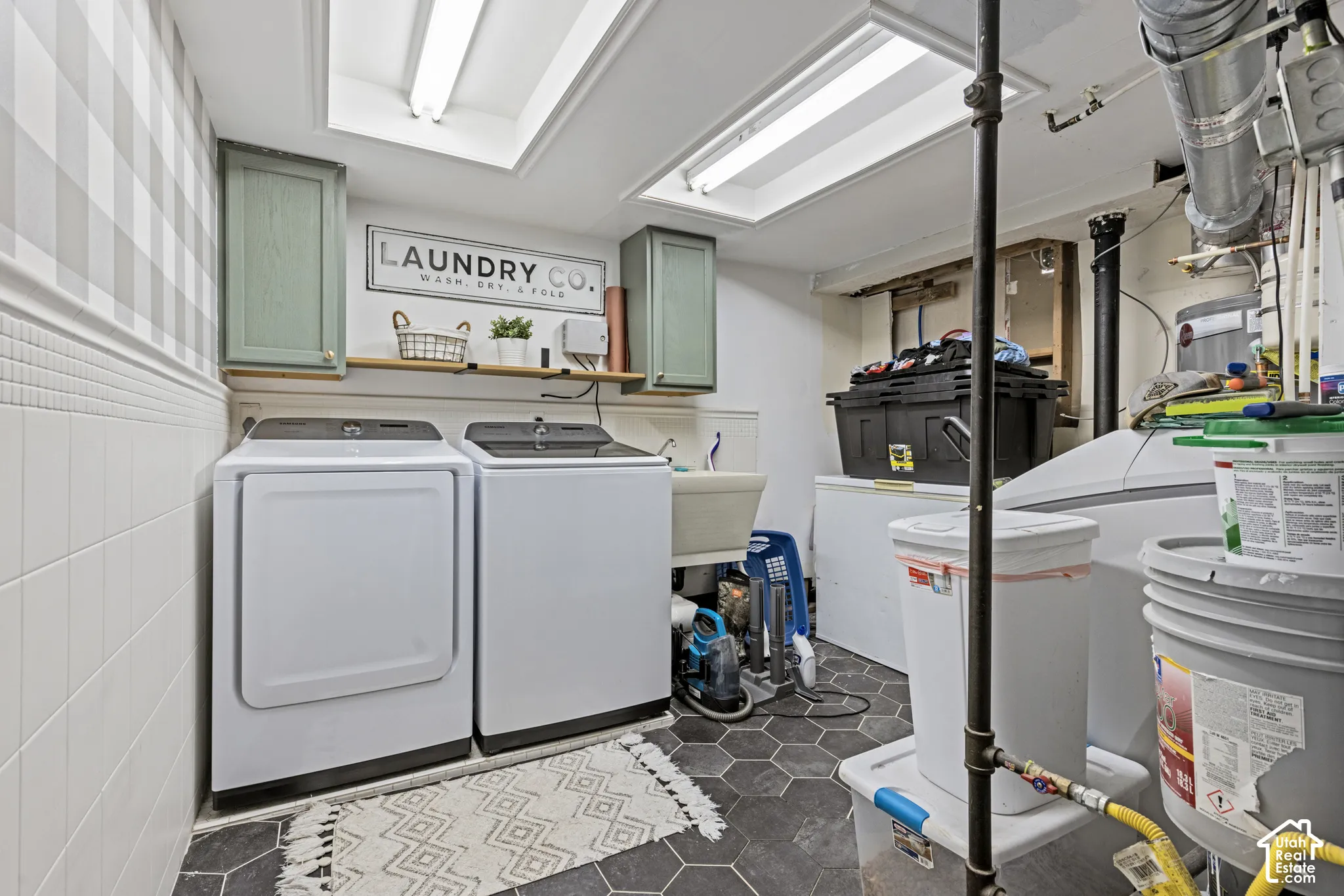 Hexagonal floor tile, ceiling-mounted lighting, recessed ceiling skylight, wall-mounted cabinetry, and built-in utility sink