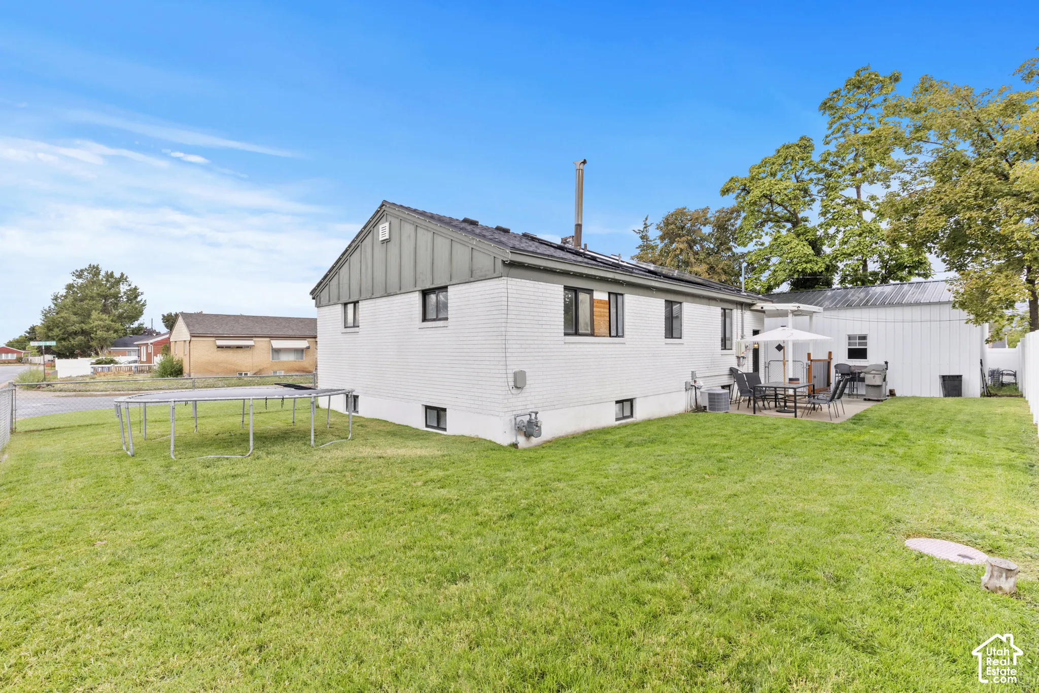 Modern farmhouse residence with expansive manicured lawn, mature landscaping, and metal roof detailing