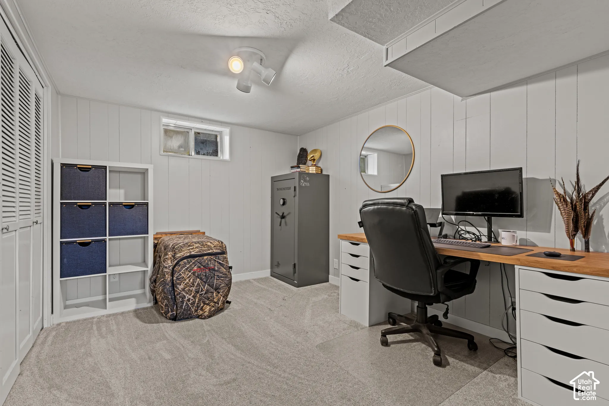 Carpeted room with paneled walls, a built-in wood-finish desk, and a window