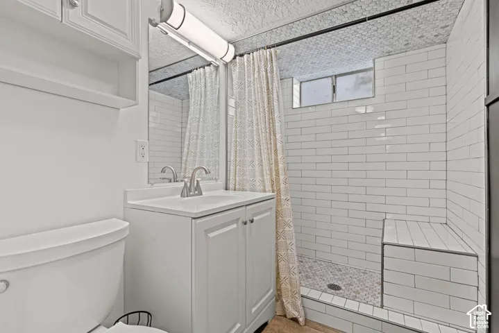 Modern bathroom featuring subway tile surround, a frameless glass shower enclosure with mosaic tile flooring, white vanity cabinetry with integrated sink and brushed nickel faucet, and a white ceramic toilet