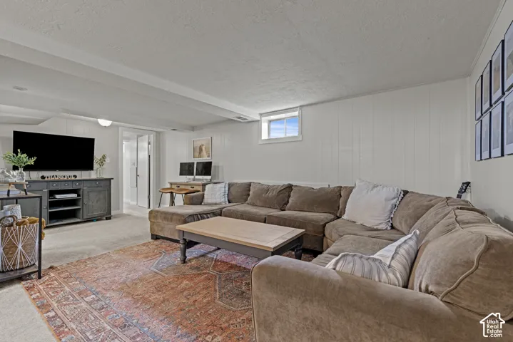 Recessed lighting, wood-finish wall paneling, built-in media console, and a window for natural light