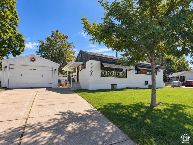White brick exterior with black accents, covered porch entry, and an attached two-car garage