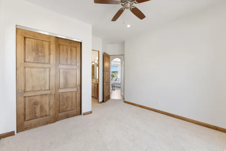 Sliding wood-paneled doors, wood-finish ceiling fan, recessed lighting, and light-toned carpeting