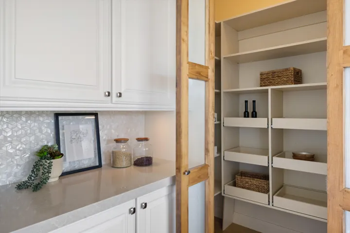 White shaker-style cabinetry with chrome hardware, geometric tile backsplash, and a light-toned countertop
