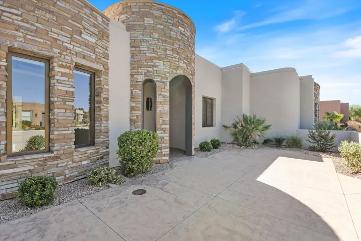 Stucco exterior with stone accents, arched entryway, and desert landscaping