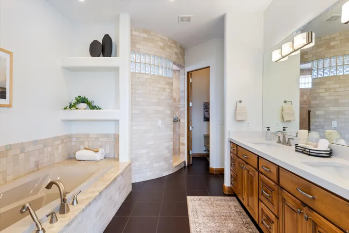 Dual vanity with white countertops, wood-finish cabinetry, and chrome fixtures