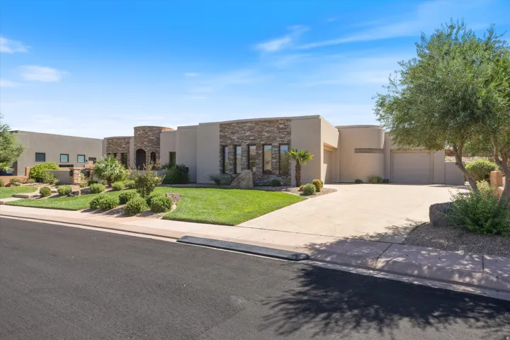 Modern stucco exterior with stone accents, a multi-car driveway, and manicured landscaping