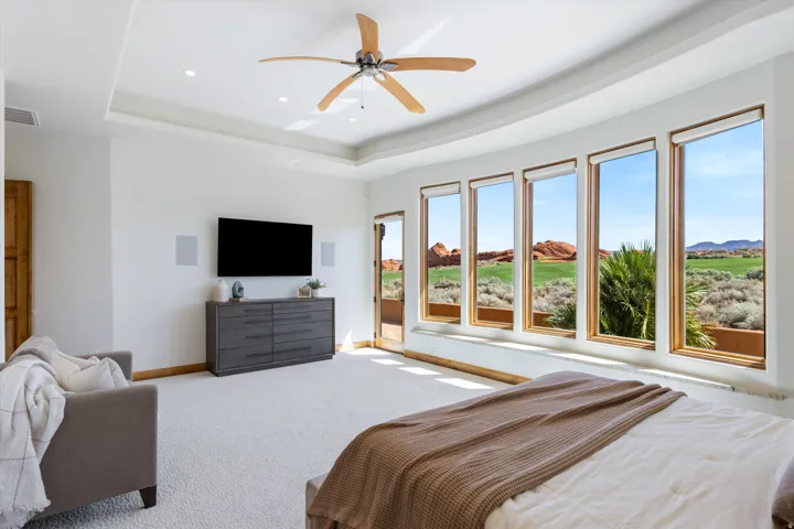 Tray ceiling, recessed lighting, ceiling fan, carpeting, and multiple floor-to-ceiling windows