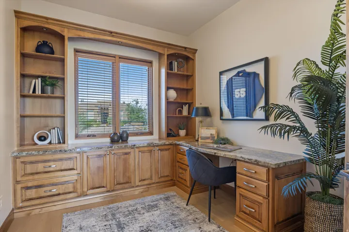 Built-in wooden cabinetry with integrated shelving, a desk, and a window