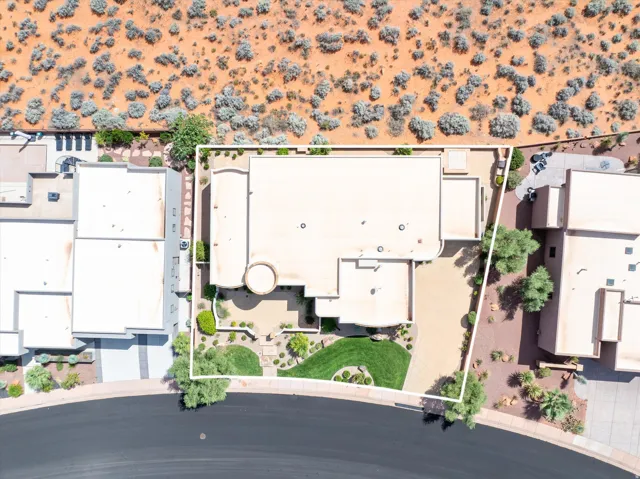 Desert landscape with a flat roofline, circular architectural feature, and a paved driveway
