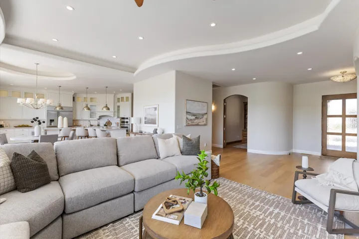 Recessed lighting, wood-finish flooring, arched doorways, white cabinetry, and stainless steel appliances