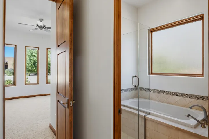 Built-in bathtub with glass enclosure, mosaic tile accent, and light-toned tile surround