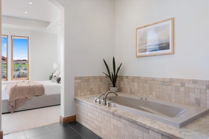 Soaking tub with a tiled surround featuring a decorative mosaic border